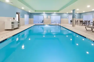a large swimming pool with blue water in a building at Holiday Inn Express & Suites - Milan - Sandusky Area by IHG in Milan