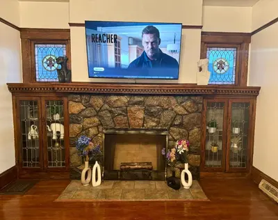 a living room with a fireplace with a flat screen tv at The House Hotel Elmwood in Lakewood