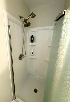 a bathroom with a shower with a glass door at The House Hotel Elmwood in Lakewood