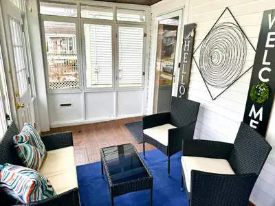 a screened in porch with chairs and a table at The House Hotel Elmwood in Lakewood