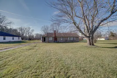 a small house in a field with a tree at Quaint Youngstown Home about 2 Mi to Boardman Park! in Youngstown