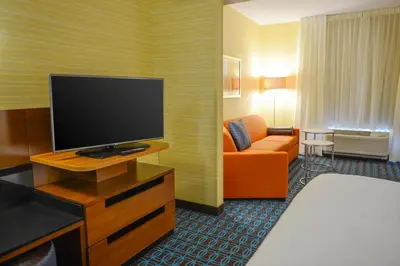 a hotel room with a television and a couch at Fairfield Inn and Suites Canton South in Canton