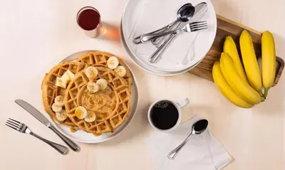 a table topped with a plate of waffles and bananas at Drury Plaza Hotel Cincinnati Florence in Florence