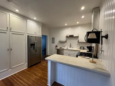 a kitchen with white cabinets and a stainless steel refrigerator at Beautiful Bungalow on Main in Madison