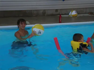 a woman and a boy playing with a ball in a swimming pool at Bay Lodging Resort in Put-in-Bay