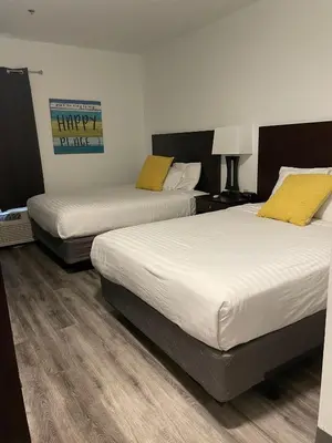 two beds in a hotel room with white and yellow pillows at Bay Lodging Resort in Put-in-Bay