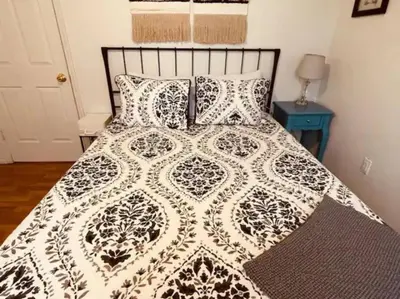 a bed with a black and white comforter and pillows at Rise and Shine! A Gorge-ous cabin! in Korea