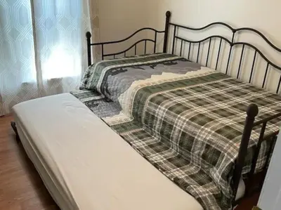 a bed with a plaid blanket on top of it at Rise and Shine! A Gorge-ous cabin! in Korea