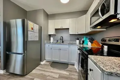 a kitchen with white cabinets and a stainless steel refrigerator at Sleek remodeled Design 2 Bed Trenton, OH Apartment in Trenton