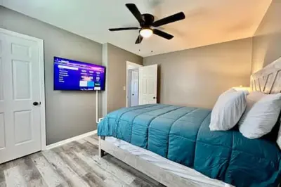 a bedroom with a bed with a ceiling fan and a tv at Charming, Stylish remodeled Trenton Apartment in Trenton