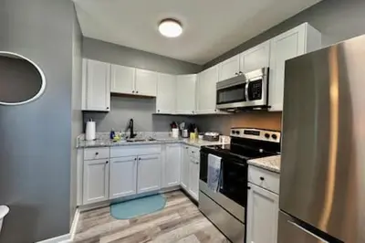 a kitchen with white cabinets and a blue stool at Charming, Stylish remodeled Trenton Apartment in Trenton