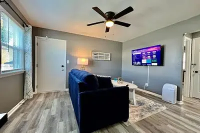 a living room with a blue couch and a ceiling fan at Charming, Stylish remodeled Trenton Apartment in Trenton