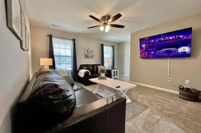 a living room with a leather couch and a table at Brand New Home Walking distance to Spooky Nook in Hamilton