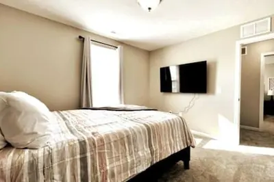 a bedroom with a bed and a tv on the wall at NEW Executive Home in Germantown, OH in Germantown