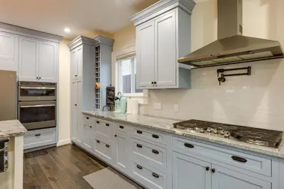 a kitchen with white cabinets and a stove top oven at Charming Cincinnati Home with Spacious Deck! in Cincinnati
