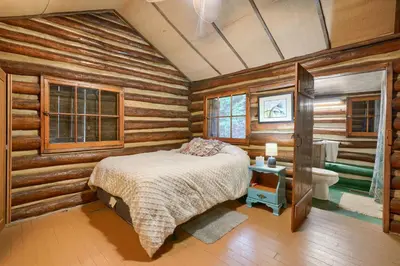a bedroom with wooden walls and a bed and a bathroom at Russell Cabin in Logan