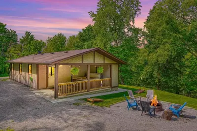 a cabin with a fireplace and chairs and a fire pit at Hideaway Pines in Logan