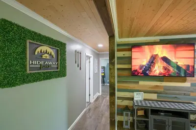 a living room with a fireplace and a tv on a wall at Hideaway Pines in Logan