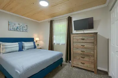 a bedroom with a bed and a flat screen tv at Hideaway Pines in Logan