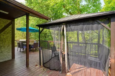 a screened in deck with a table and umbrella at Hideaway Pines in Logan