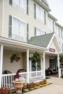 a white house with a porch and a sign on it at Coshocton Village Inn & Suites in Coshocton