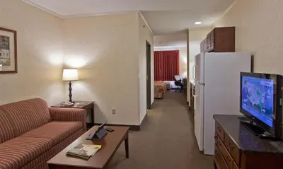 a living room with a couch and a refrigerator in a hotel room at Coshocton Village Inn & Suites in Coshocton