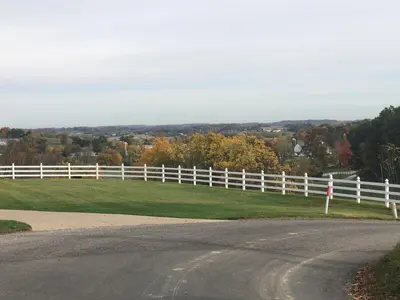 a white fence on a field with a road at The Barn at Sharp Run-Modern Barn in the heart of Amish Country in Millersburg