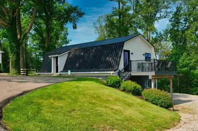 a house with a black roof and a balcony at The Barn at Sharp Run-Modern Barn in the heart of Amish Country in Millersburg