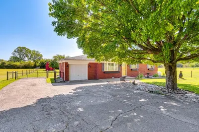 a red brick house with a tree in the driveway at 7 Mi to Depot District Richmond Home with Fire Pit in Richmond