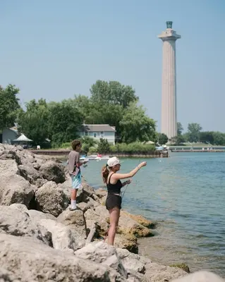 a boy and a girl standing on rocks near the water at Bayshore Resort At Put-In-Bay in Put-in-Bay