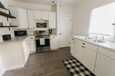 a kitchen with white cabinets and a sink and a stove at Beautiful Cape Cod House in Central Location in Dayton
