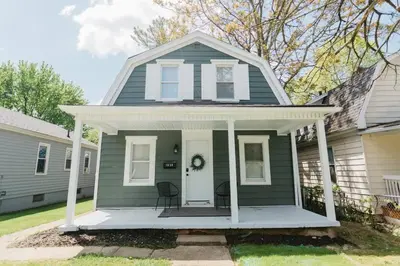 a green house with a white door and a porch at Beautiful Cape Cod House in Central Location in Dayton