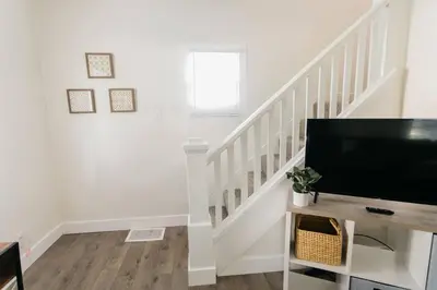 a white staircase with a flat screen tv at Beautiful Cape Cod House in Central Location in Dayton