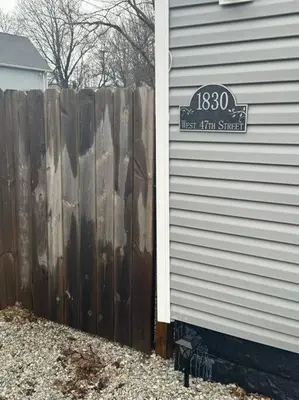 a wooden fence next to a house with a sign on it at Little house on 47th in Cleveland