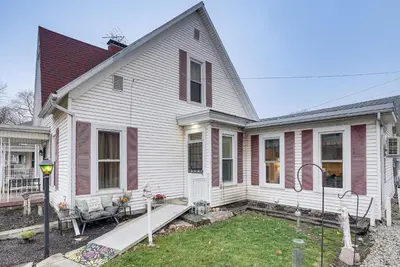 a white house with a porch and a yard at West Liberty Vacation Rental Near Mad River! in West Liberty