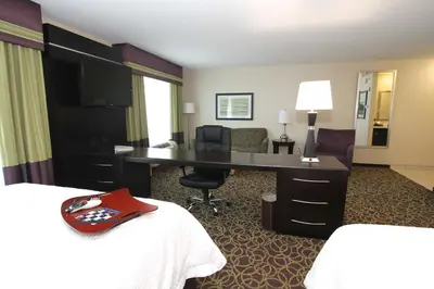 a hotel room with a desk and a room with two beds at Hampton Inn and Suites Sandusky/Milan in Milan