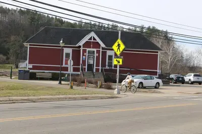 a man riding a bike in front of a red house at Athens city townhouse, 3 bedroom, 2.5 baths, Wi-Fi in Athens