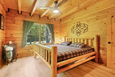 a bedroom with a bed in a log cabin at Peek A Boo Cabins: Cozy Cabin in Logan