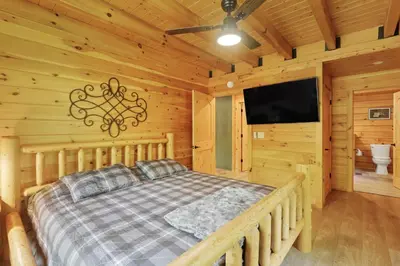 a bedroom with a bed and a flat screen tv at Peek A Boo Cabins: Cozy Cabin in Logan
