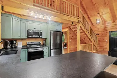a kitchen with green cabinets and a black counter top at Peek A Boo Cabins: Cozy Cabin in Logan