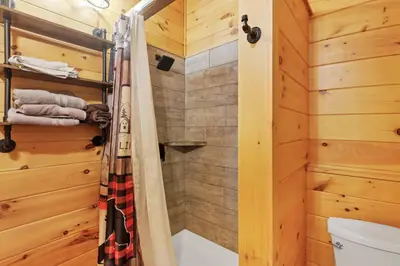 a bathroom with a shower and a toilet at Peek A Boo Cabins: Cozy Cabin in Logan