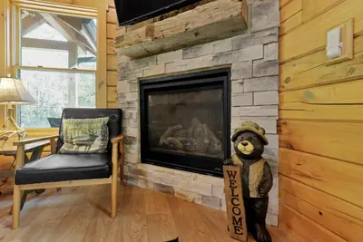 a teddy bear standing in front of a fireplace at Peek A Boo Cabins: Cozy Cabin in Logan