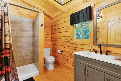 a log cabin bathroom with a toilet and a sink at Peek A Boo Cabins: Cozy Cabin in Logan