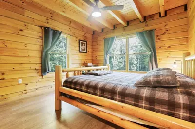 a bedroom with a bed in a log cabin at Peek A Boo Cabins: Cozy Cabin in Logan