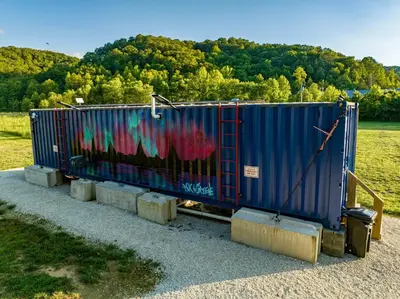 a container with graffiti on it sitting in a field at Red River Elusive Elk Glamping Tent 1 in Stanton