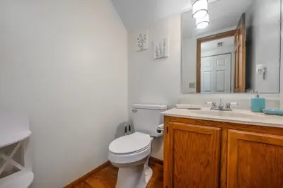 a bathroom with a toilet and a sink and a mirror at Quiet 2-Bedroom Condo with Garage and Fast Wi-Fi in Fort Wayne