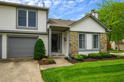 a house with a garage and green grass at Quiet 2-Bedroom Condo with Garage and Fast Wi-Fi in Fort Wayne