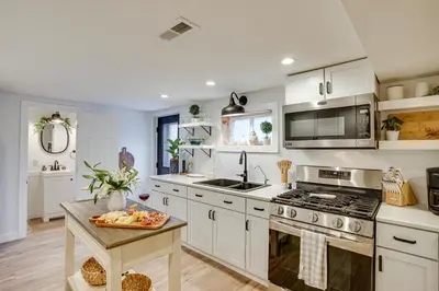 a kitchen with white cabinets and a table in it at Montpelier Lake House with Deck, Dock and Fireplace! in Montpelier