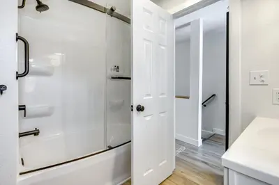 a white bathroom with a shower and a sink at Montpelier Lake House with Deck, Dock and Fireplace! in Montpelier