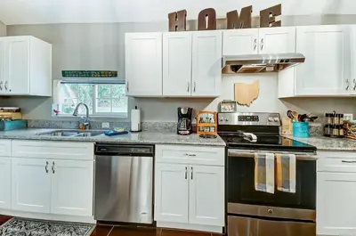 a kitchen with white cabinets and a stove top oven at Updated 3bd Cottage on Bike Trail w/ River access! in Loveland